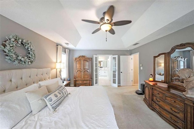 carpeted bedroom featuring ceiling fan, a raised ceiling, and ensuite bathroom