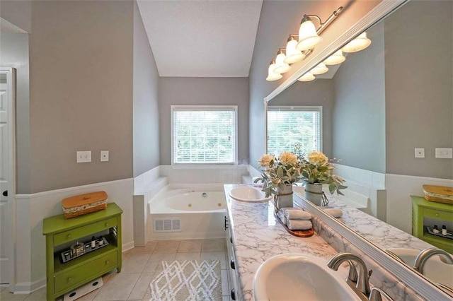 bathroom with lofted ceiling, double vanity, a tub to relax in, and tile patterned floors