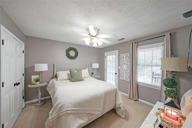 bedroom with light colored carpet, a closet, a textured ceiling, and ceiling fan