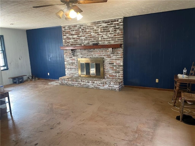 unfurnished living room with a textured ceiling, ceiling fan, a fireplace, and baseboards