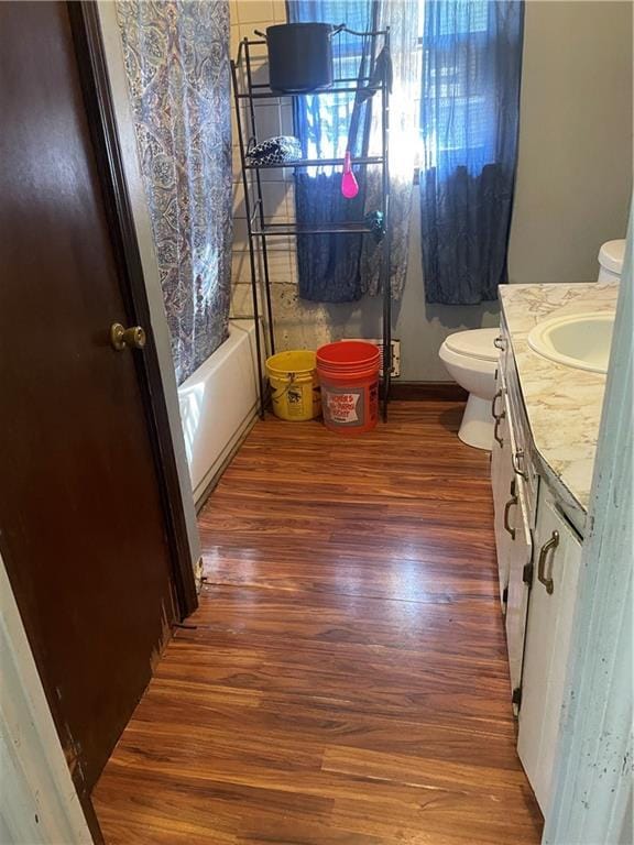 bathroom featuring toilet, shower / bath combo, wood finished floors, and vanity