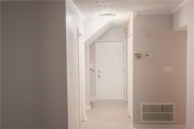 hallway featuring light hardwood / wood-style floors, ornamental molding, and a textured ceiling