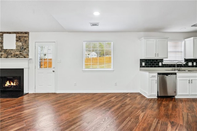 kitchen with backsplash, dishwasher, sink, and white cabinets