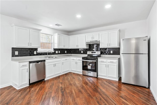 kitchen with dark wood-type flooring, stainless steel appliances, sink, and white cabinets