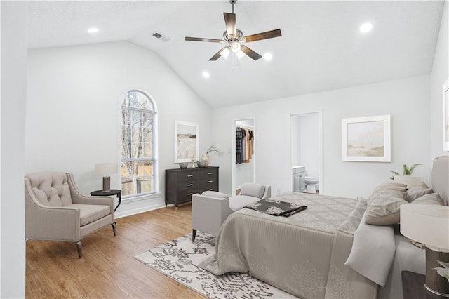 bedroom with multiple windows, lofted ceiling, a spacious closet, and light hardwood / wood-style flooring