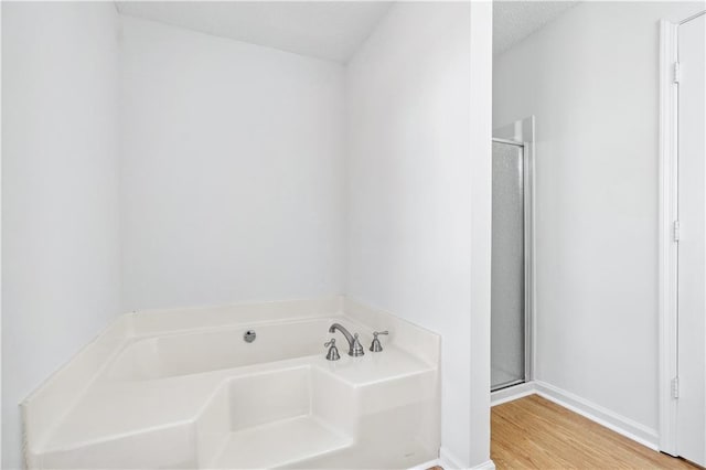 bathroom with hardwood / wood-style flooring, plus walk in shower, and a textured ceiling