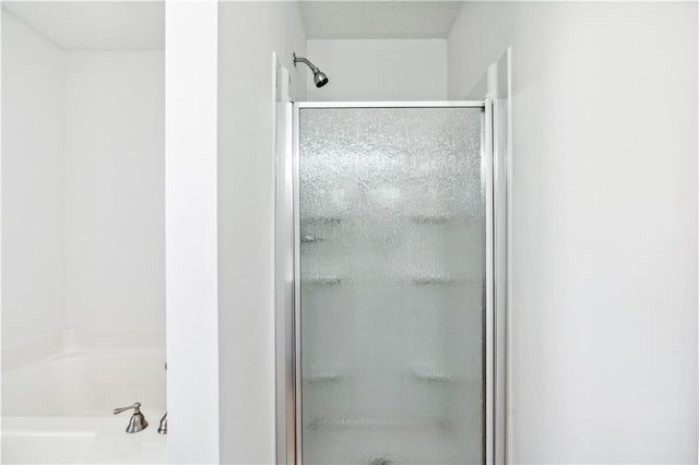 bathroom with shower with separate bathtub and a textured ceiling