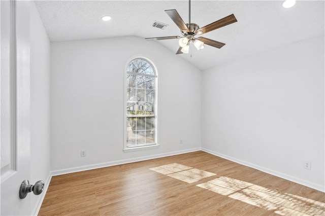 spare room featuring lofted ceiling, a textured ceiling, ceiling fan, and light wood-type flooring