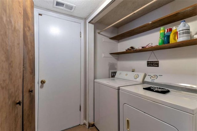 laundry area featuring visible vents, washing machine and dryer, a textured ceiling, and laundry area