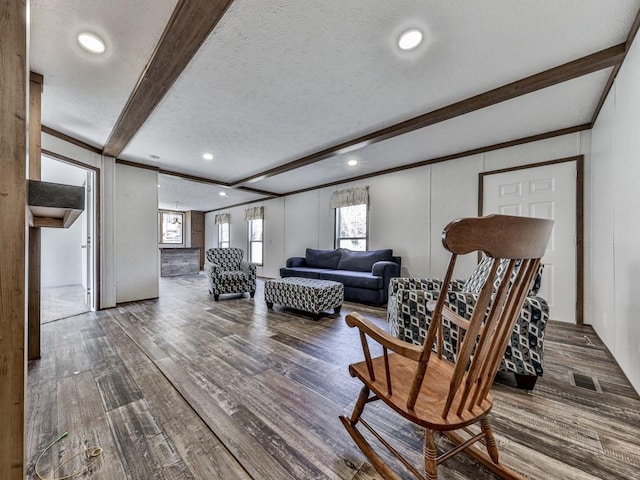 living room featuring beam ceiling, a textured ceiling, and hardwood / wood-style flooring