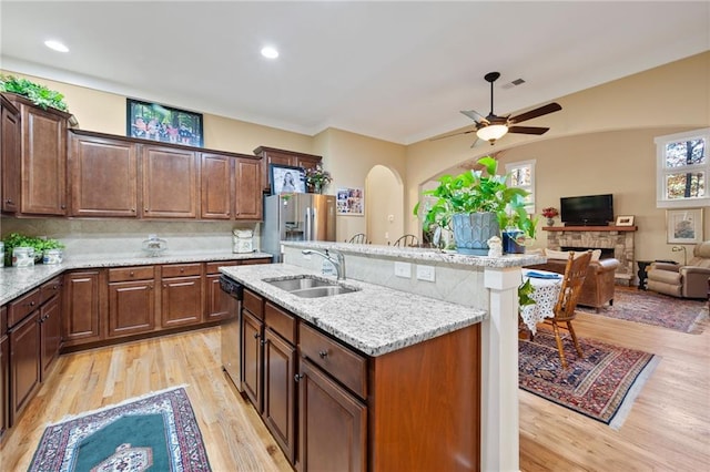 kitchen featuring a center island with sink, light hardwood / wood-style floors, ceiling fan, and a fireplace