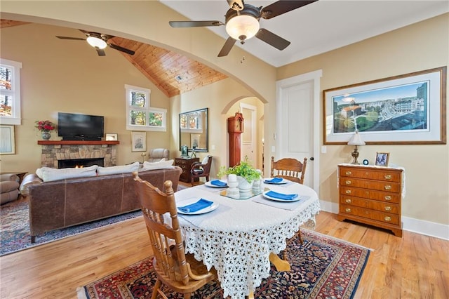 dining room featuring ceiling fan, lofted ceiling, light hardwood / wood-style flooring, and a fireplace