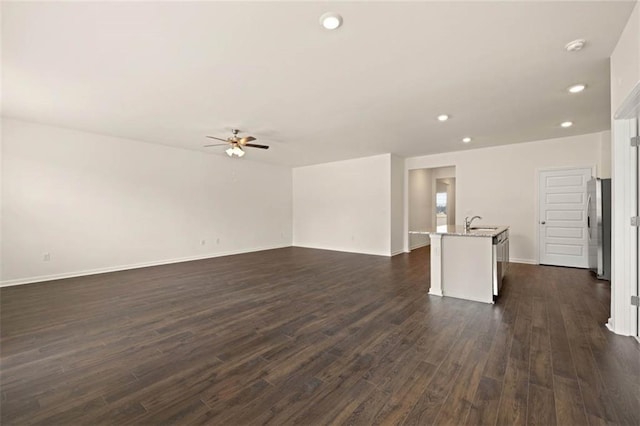 unfurnished living room with baseboards, a ceiling fan, dark wood-style flooring, a sink, and recessed lighting