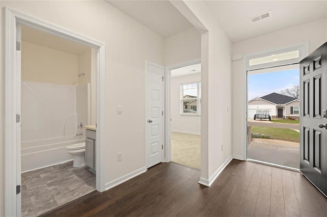 foyer featuring dark wood-type flooring, visible vents, and baseboards