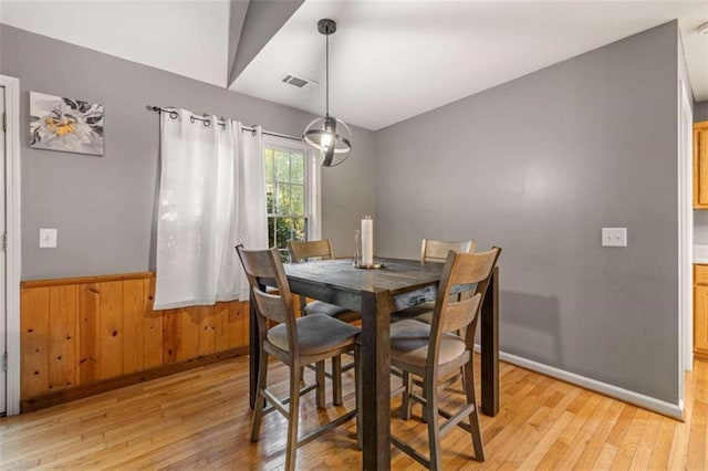 dining area with wood walls and light wood-type flooring