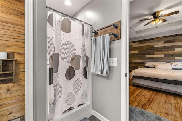 bathroom featuring ceiling fan, wood walls, a shower with shower curtain, and hardwood / wood-style flooring