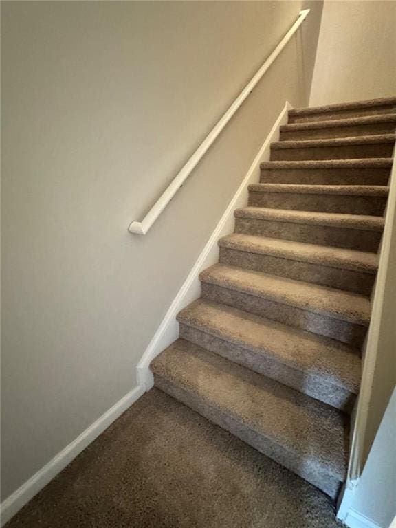 stairway with baseboards and carpet