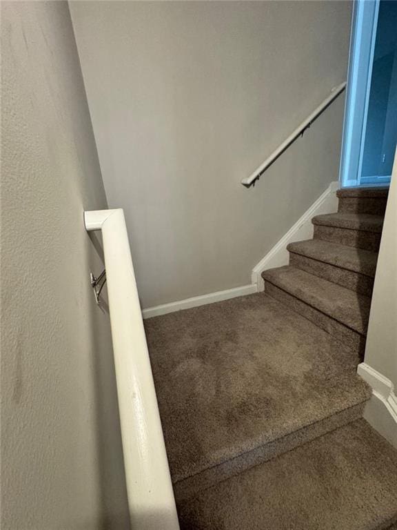 staircase featuring baseboards and carpet