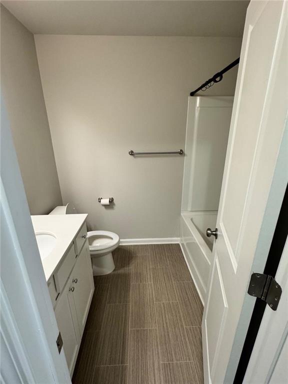 bathroom featuring vanity, toilet, bathtub / shower combination, and baseboards