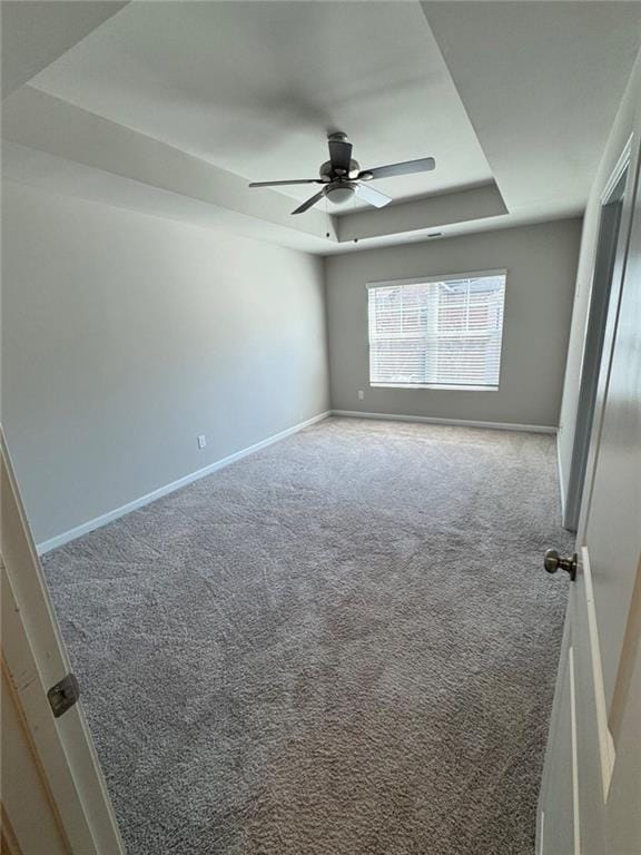 unfurnished bedroom featuring a tray ceiling, carpet floors, baseboards, and ceiling fan