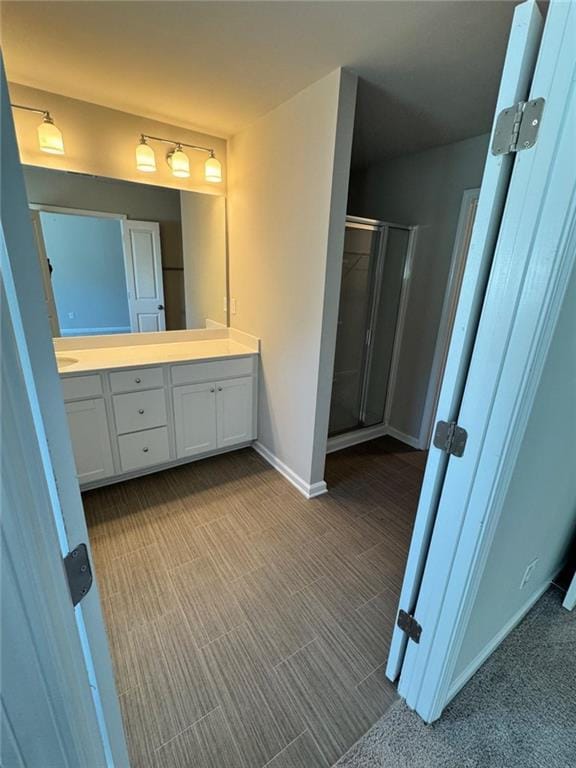 full bathroom with vanity, a shower stall, and baseboards