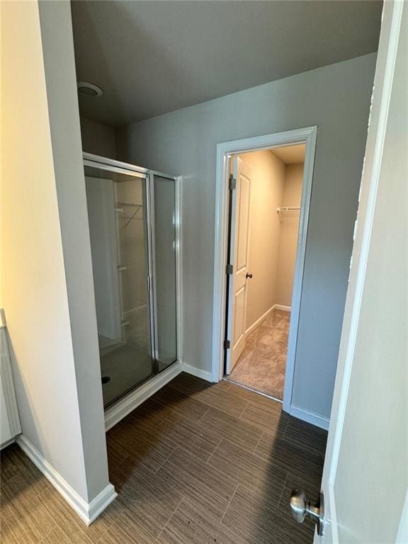 bathroom with baseboards, a shower stall, and a spacious closet