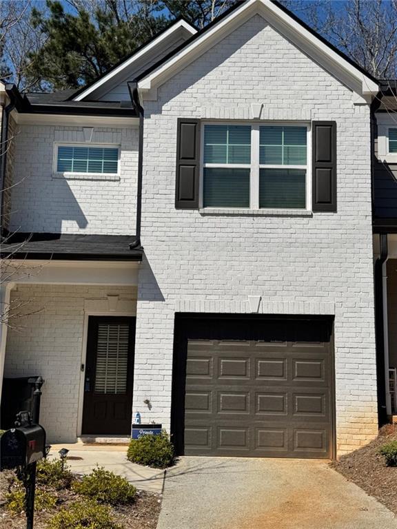 view of front of house featuring a garage, brick siding, and driveway