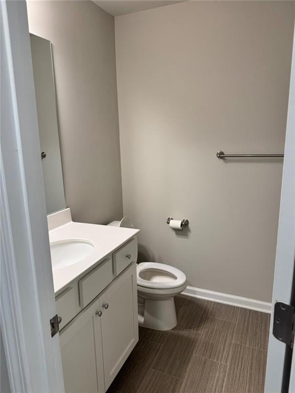 bathroom featuring baseboards, toilet, and vanity