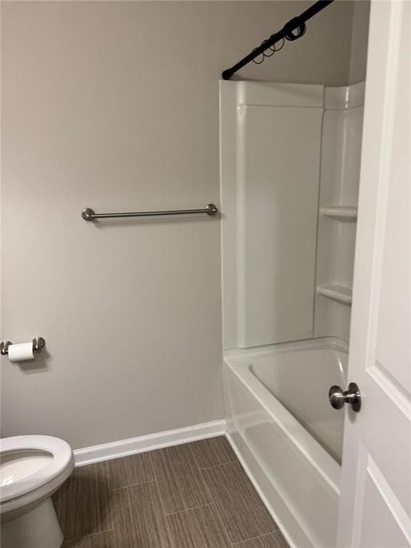 bathroom with tub / shower combination, toilet, and baseboards