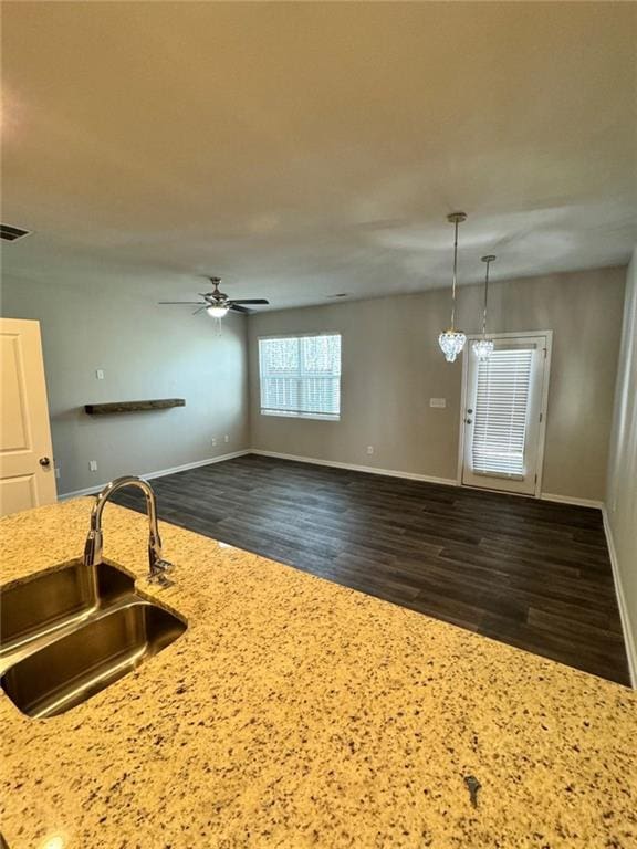 kitchen featuring a sink, visible vents, light stone countertops, and dark wood finished floors