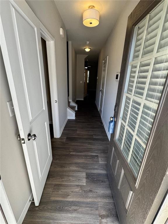 corridor featuring baseboards and dark wood-style flooring