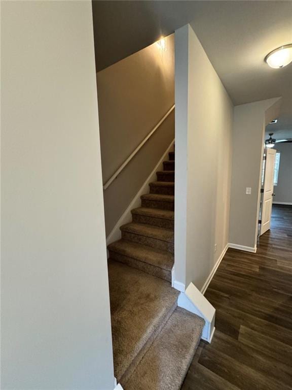 staircase with wood finished floors, baseboards, and ceiling fan