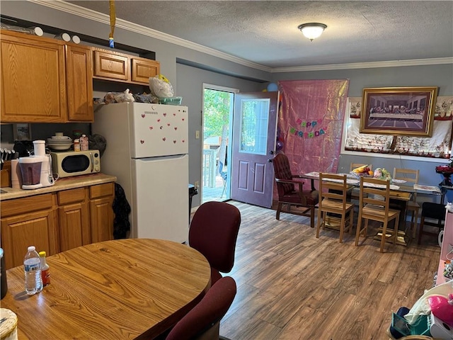 703 Jack Sharp Rd, Colbert, GA 30628 - kitchen with freestanding refrigerator, stainless steel microwave, wood finished floors, crown molding, and a textured ceiling