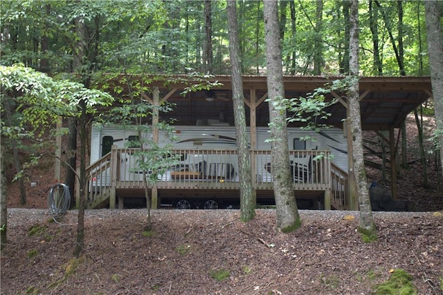 rear view of property with ceiling fan, a deck, and a wooded view