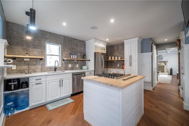 kitchen featuring sink, wooden counters, appliances with stainless steel finishes, white cabinetry, and a center island