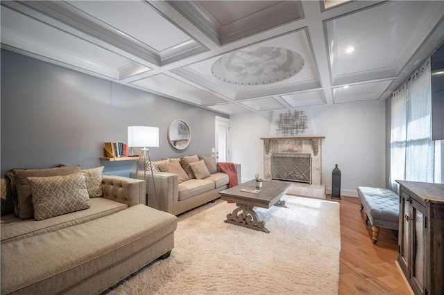 living room with coffered ceiling, crown molding, light wood-type flooring, beamed ceiling, and a premium fireplace