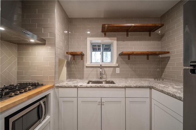 kitchen with light stone counters, sink, white cabinets, and appliances with stainless steel finishes