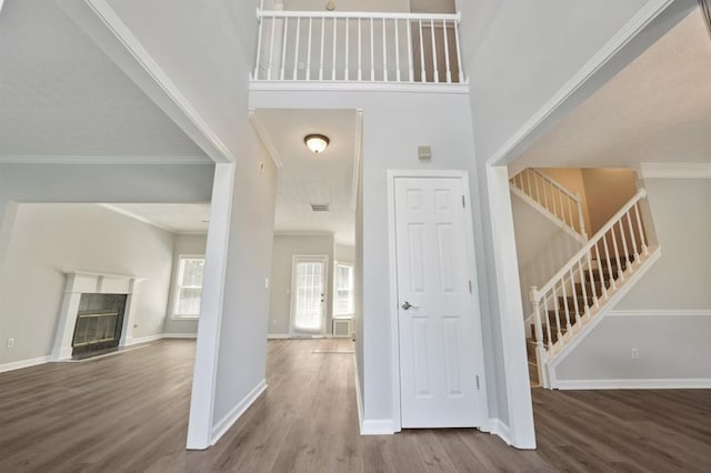 entryway featuring a towering ceiling, crown molding, and hardwood / wood-style flooring