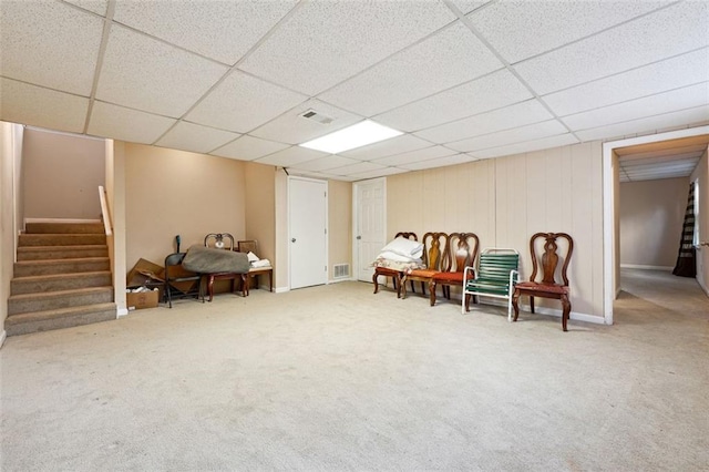 living area with carpet, visible vents, a paneled ceiling, and stairway