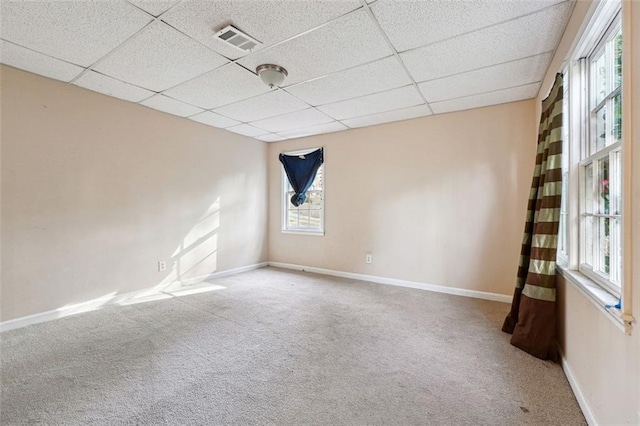 carpeted spare room featuring baseboards, visible vents, and a drop ceiling