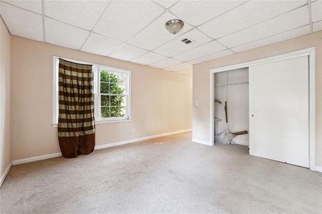 unfurnished bedroom featuring a paneled ceiling, carpet floors, visible vents, baseboards, and a closet