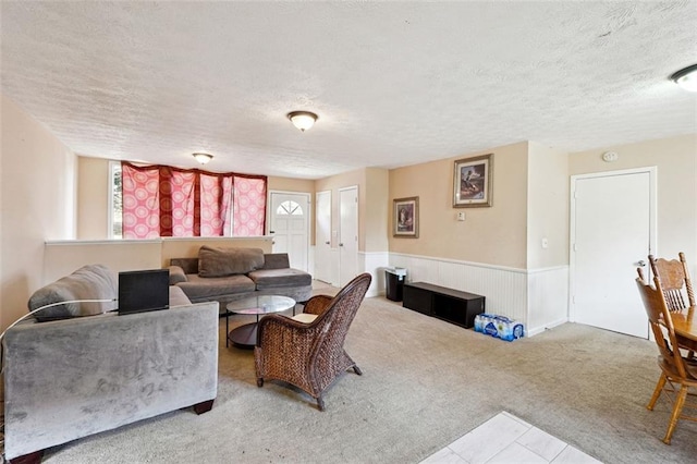 living area featuring light carpet, a textured ceiling, and wainscoting