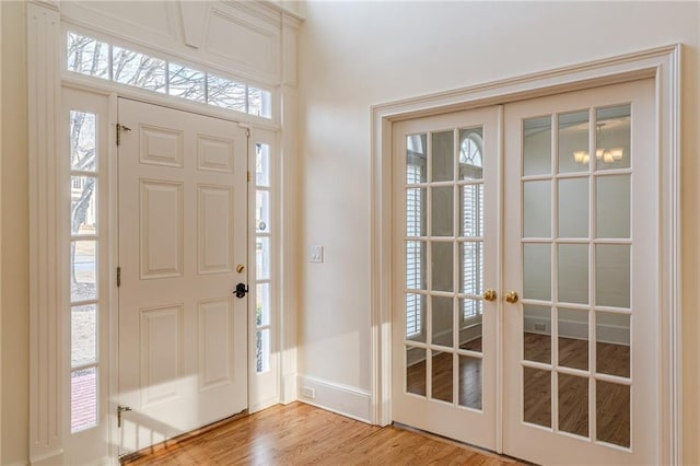 foyer entrance featuring french doors, baseboards, and light wood finished floors