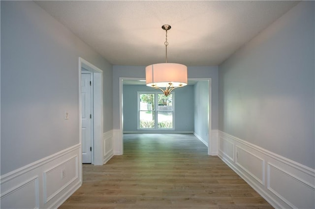 9050 Brockham Way, Alpharetta, GA 30022 - unfurnished dining area with a decorative wall, a wainscoted wall, light wood-style flooring, and a chandelier