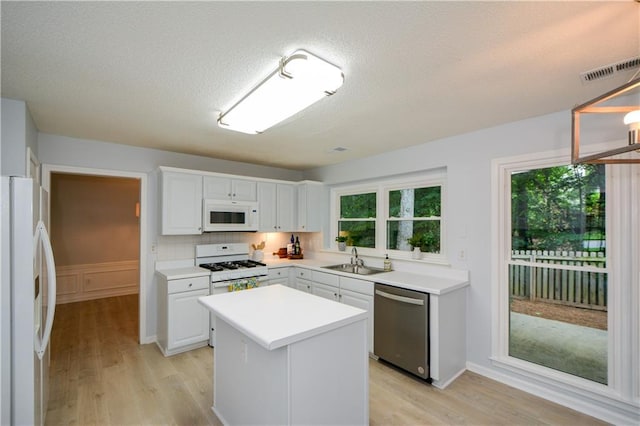 9050 Brockham Way, Alpharetta, GA 30022 - kitchen featuring white appliances, a sink, light wood-style flooring, white cabinets, and a textured ceiling