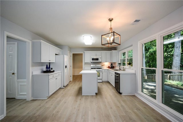 9050 Brockham Way, Alpharetta, GA 30022 - kitchen with white appliances, a chandelier, light wood-type flooring, light countertops, and a kitchen island