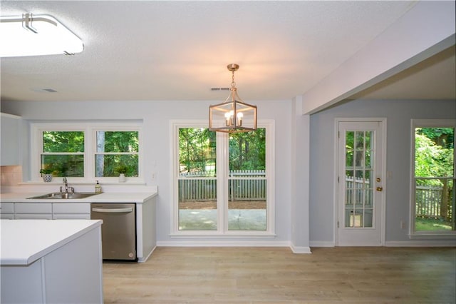 9050 Brockham Way, Alpharetta, GA 30022 - kitchen featuring stainless steel dishwasher, a sink, light countertops, light wood-type flooring, and a chandelier