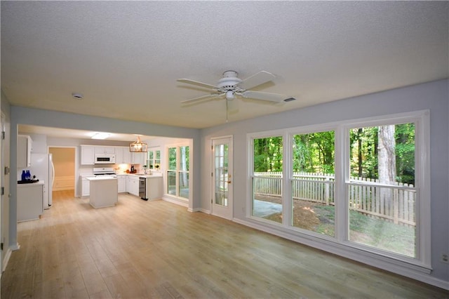 9050 Brockham Way, Alpharetta, GA 30022 - unfurnished living room featuring light wood-style floors, ceiling fan, a textured ceiling, baseboards, and a sink