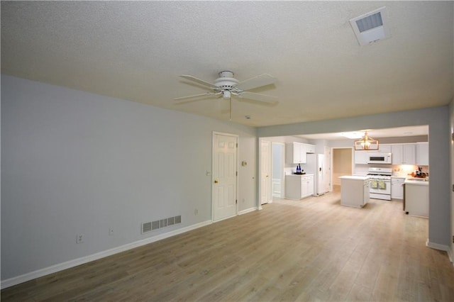 9050 Brockham Way, Alpharetta, GA 30022 - unfurnished living room featuring light wood-type flooring, baseboards, ceiling fan, a chandelier, and a textured ceiling