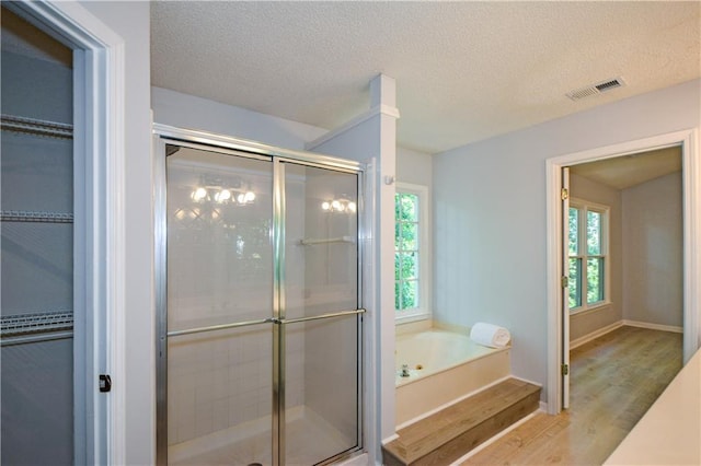 9050 Brockham Way, Alpharetta, GA 30022 - bathroom featuring wood finished floors, a shower stall, a bath, a spacious closet, and a textured ceiling